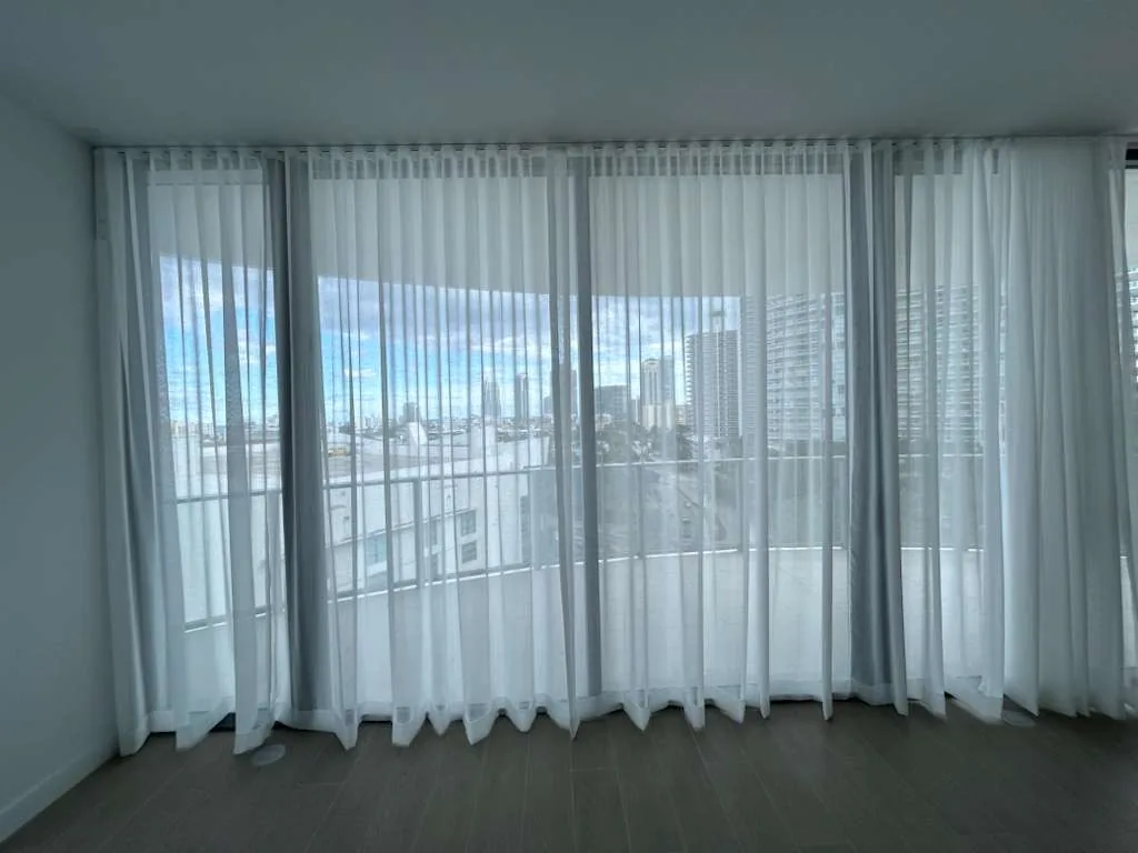 Light-filtering drapery across a corner of windows