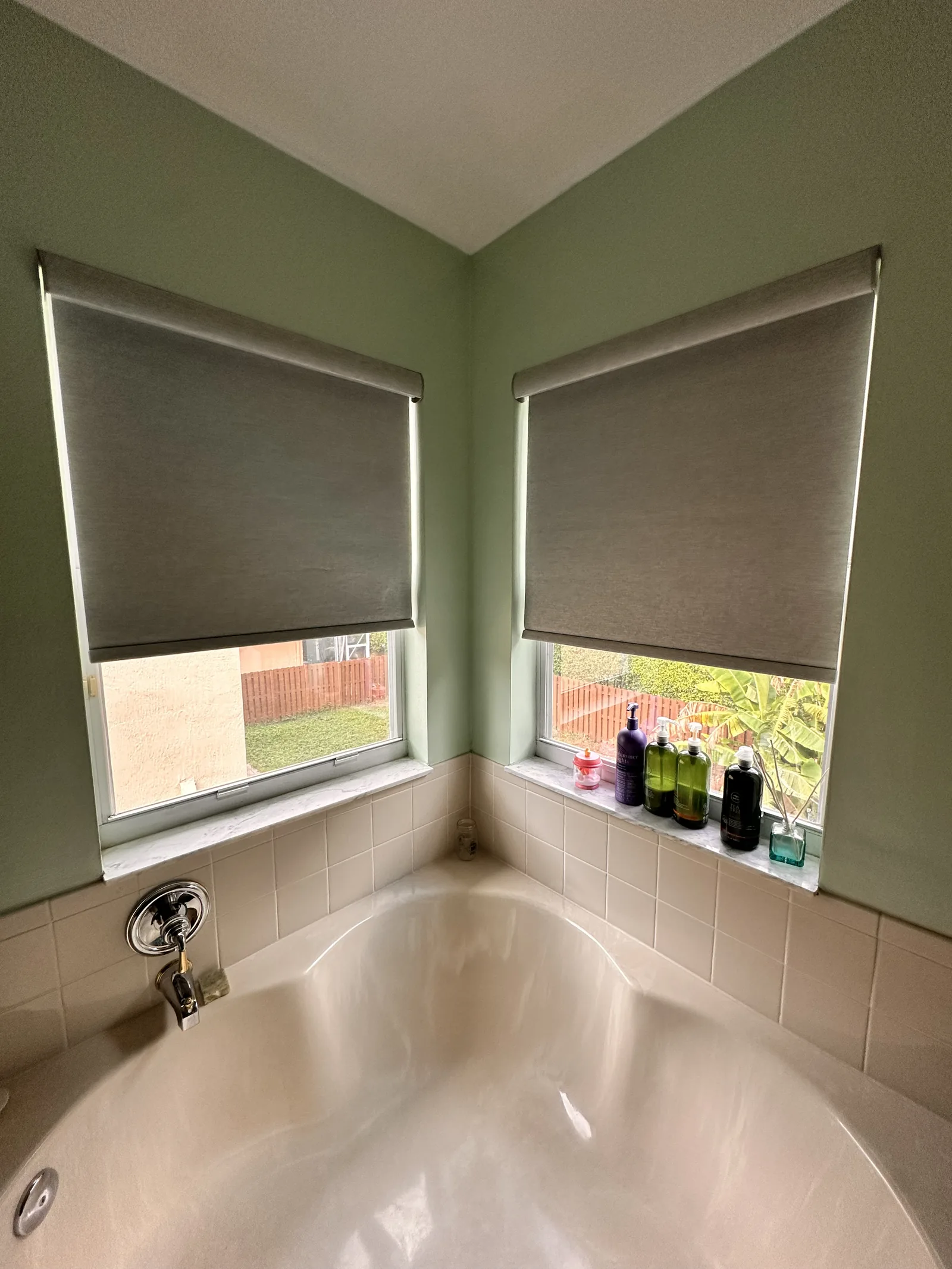 Blackout roller shades framing a corner bathtub