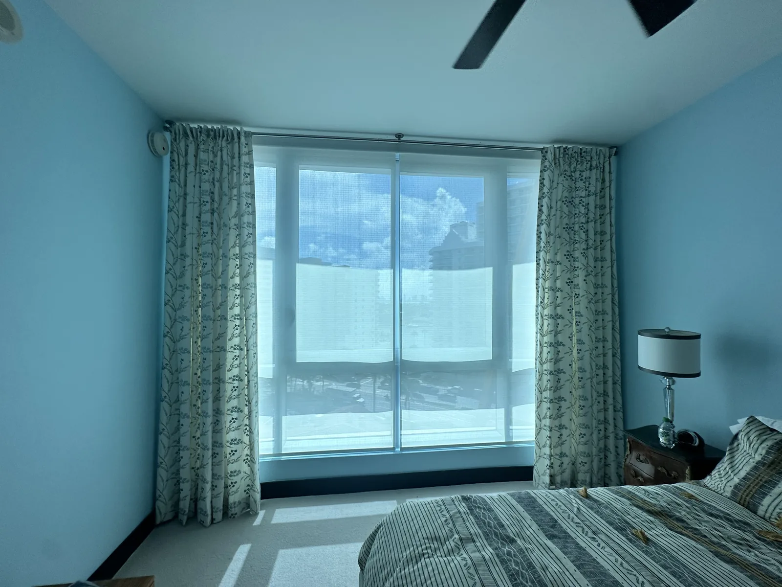 Roller screen shade behind drapery in a bedroom