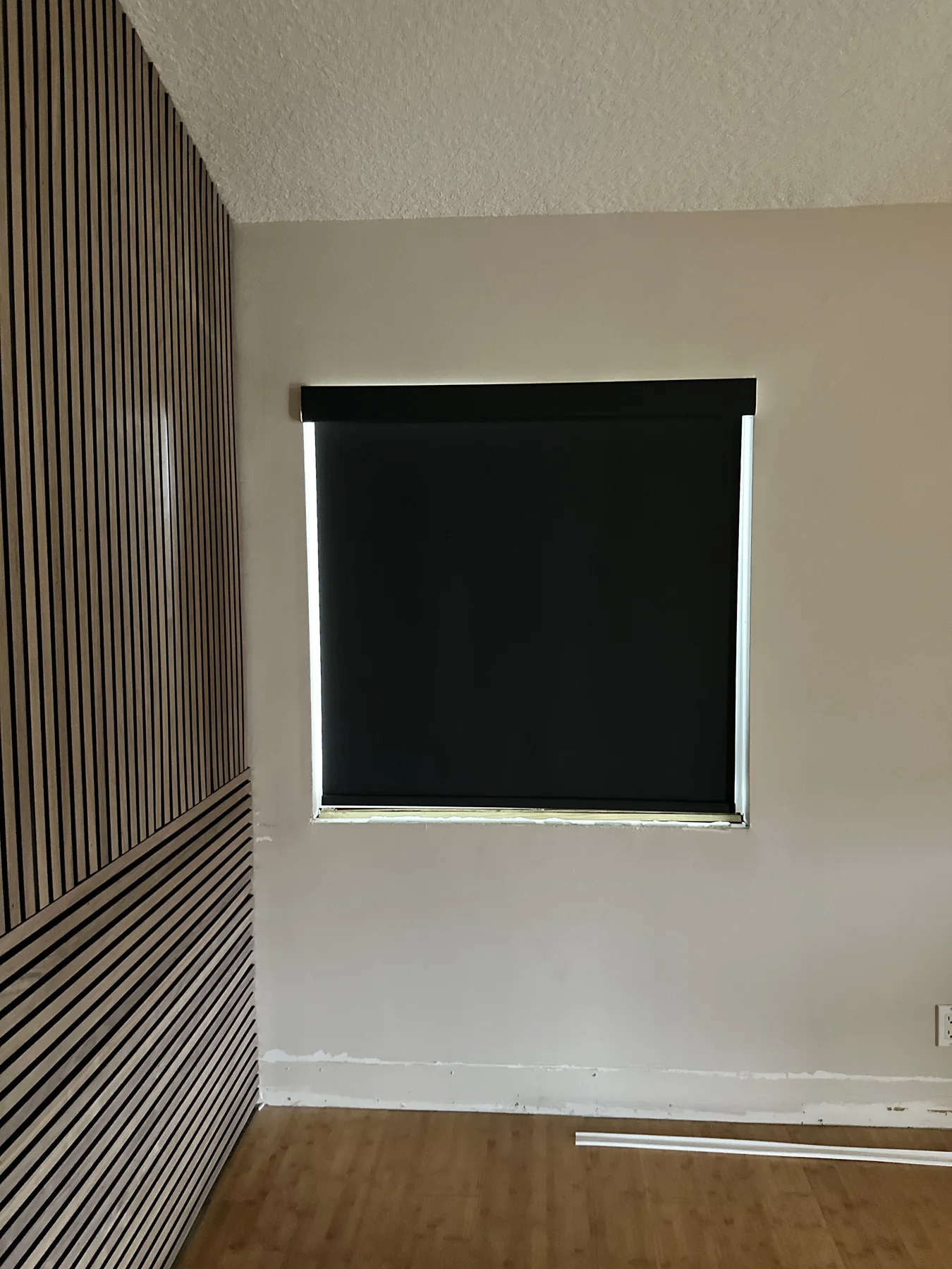 Blackout roller shade against a wood-slat accent wall